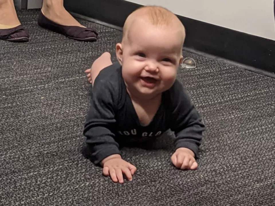 Baby scrawling on the floor, giving sweet smile in Oct 2020.