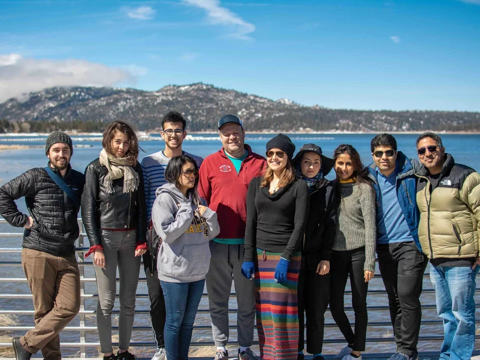 Group of Butte Lab employees dressed in jackets, standing in front of Big Bear Lake March 2019.